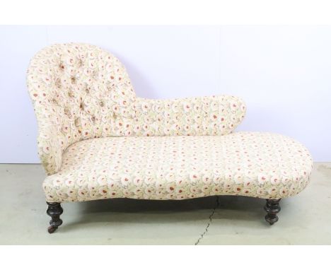 Edwardian mahogany chaise longue, with upholstered shaped button back above turned legs and casters, approximately 81cm high 