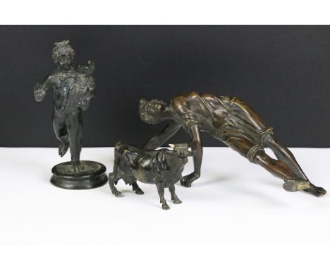 A small group of three bronze figures to include two traditional figures together with a cow. 