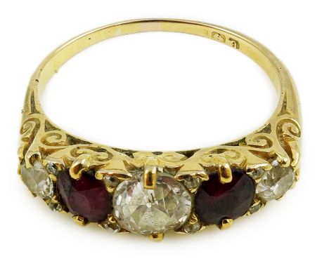 A late Victorian 18ct gold, two stone ruby and three stone diamond set half hoop ring, with carved setting, size P, gross wei