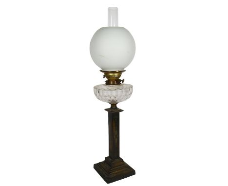 An Antique engraved brass oil lamp with glass font, chimney and globular shade, H70cm 