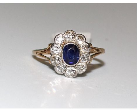 A sapphire and diamond cluster ring collet-set an oval sapphire within a border of ten old brilliant-cut diamonds, in 18ct ye