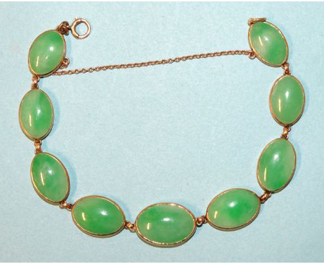 A bracelet of nine oval jade cabochons in gold spectacle mounts, (unmarked, tests as 14k approximately), 19cm, 15g.