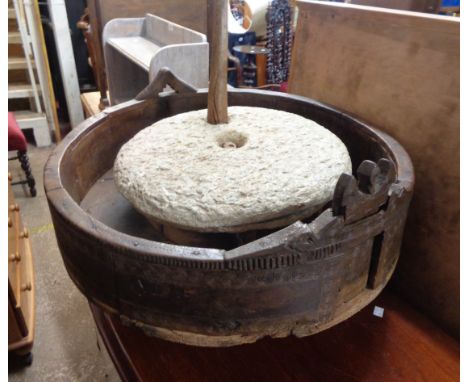 An ethnic two stone grain grinding wheel, set in a 64cm hardwood base with incised repeat roundel decoration and decorated ga