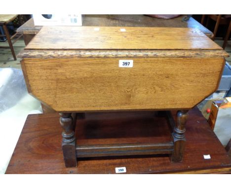 A small golden oak swivel-top table, set on a joint stool style base with bobbin turned supports