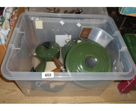 A crate containing four Le Crueset cast iron and enamel saucepans in the green colourway