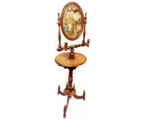 A Victorian oak nightstand with central bevelled oval swing mirror and flanking folding candle holders, over a platform with 