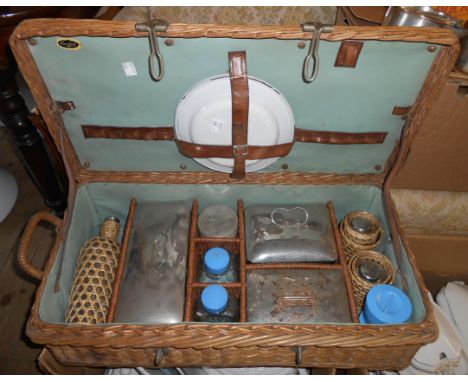 An old Handiest wicker picnic basket and contents, including metal boxes, enamel plates, etc.