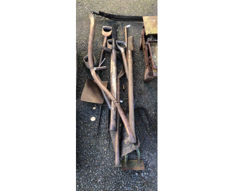 A selection of old garden tools including spades, forks, scythe, etc.