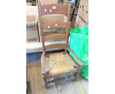 An old country style stained wood ladder back elbow chair with woven rush seat panel, set on turned front supports