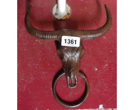 A modern cast iron towel holder in the form of a steer skull with ring and antiqued finish