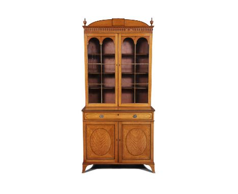 A GEORGE III INLAID SATINWOOD BREAKFRONT BOOKCASE IN THE MANNER OF GILLOWS, C.1800  the arched top cornice with urn finials a