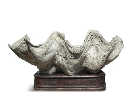 NATURAL HISTORY  A GIANT FOSSIL CLAM SHELL, TRIDACNA GENUS  on a carved timber stand inscribed “The Oriente”  100cm wide