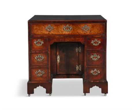 A GEORGE II WALNUT KNEEHOLE DESK, c.1730,  of compact rectangular form, the cross banded top above a long frieze drawer and r