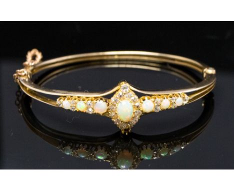 An Edwardian opal and diamond cluster yellow gold bangle, with opal and diamond set shoulders, marquise shaped cluster with c