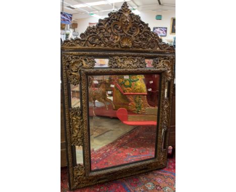 A large 19th Century wall looking glass of Baroque design, gilt metal scroll mounts on the cushion frame, bevelled glass, 100