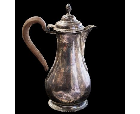 An Edwardian silver small coffee pot or hot water jug, pear shaped the plain body engraved with a crest, with acanthus spout 