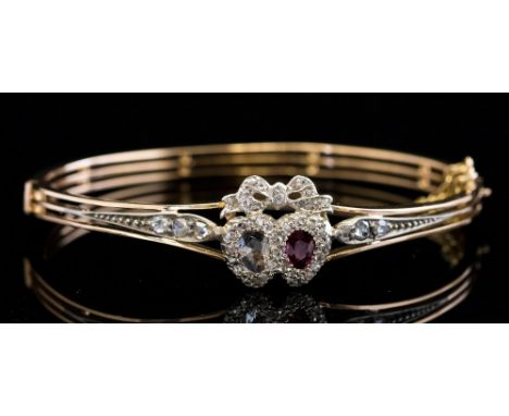 A diamond and ruby sweetheart bangle, circa 1900, the front with pierced double heart-shape mount having bow surmount set num