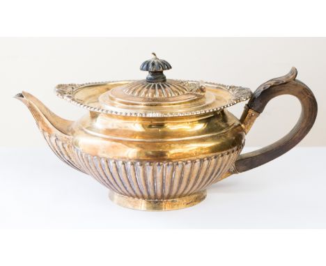 An Edwardian silver-gilt teapot, shaped circular with gadroon border and fluted section, the hinged cover with ebony pagoda s