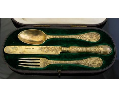 A Victorian silver-gilt Christening set comprising spoon, fork and knife of unusual pattern, each handle engraved with a cres