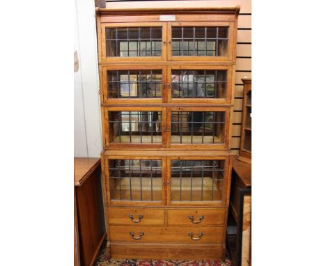 A George V oak stacking bookcase, the top with a silver plaque inscribed and dated 1924, having four tiers, the base section 