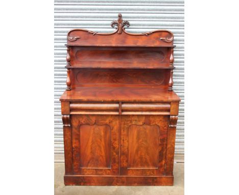 A Victorian mahogany chiffonier, the upper section with two shelves raised on octagonal baluster supports, the back with a ce