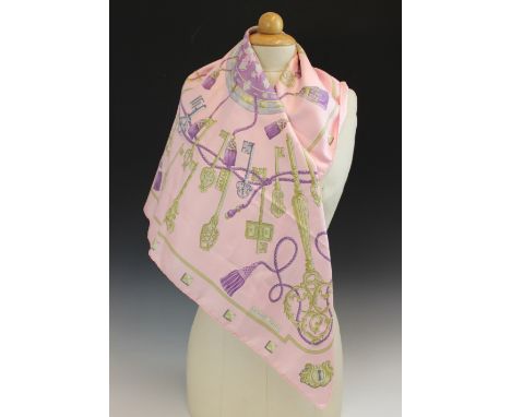 An Hermes silk scarf, in the 'Les Cles' pattern, in pink, lilac and gold tones, with rolled hems, 89cm x 89cm, within Hermes 