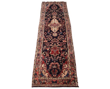 An Iranian wool runner, in red, blue and ivory colorways, the all over foliate design upon a cobalt blue ground, within three