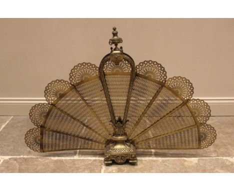 A brass folding peacock spark guard, early 20th century, with an urn finial above nine fretwork fan shaped panels, within an 