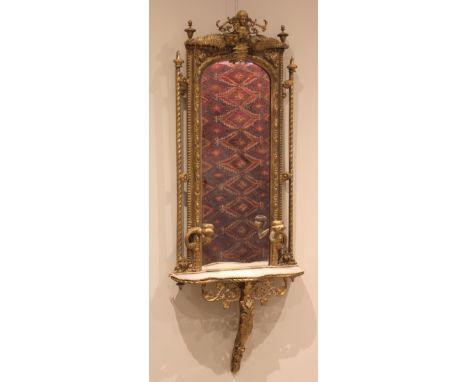 A Victorian giltwood and gesso wall mirror and shelf, the arched frame decorated with fern leaves and classical masks, leadin