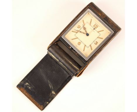 A Jaeger LeCoutre travel alarm clock, the square cream dial with baton markers and Arabic numerals, set to a silver coloured 