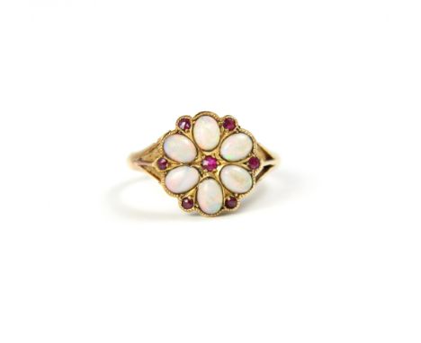 An 18ct yellow gold opal and untested ruby cluster ring, the oval cabochon opals within a petal design with red stone detail,