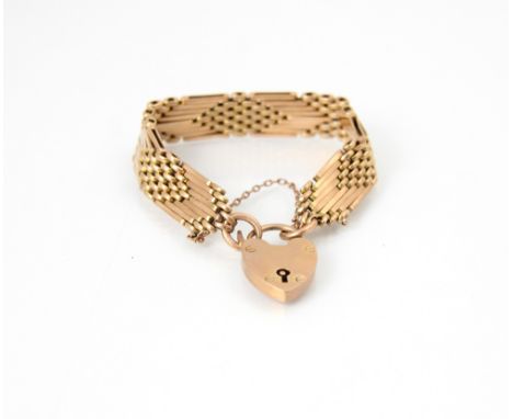 A yellow metal gate link style bracelet, the stylised gate links interspersed with mesh links, suspending a padlock heart fas