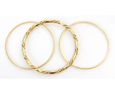 A pair of yellow metal bangles, with applied grooved detail, each engraved ‘22k’ 18gms, with a further gold coloured twist ba
