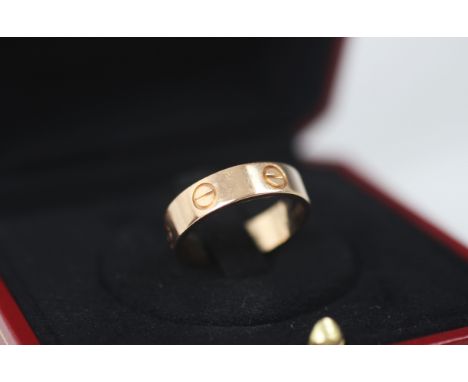 A rose gold 'Love' ring, by Cartier, the polished band ring with six screw head motifs, stamped to interior 'Cartier LVC821 A