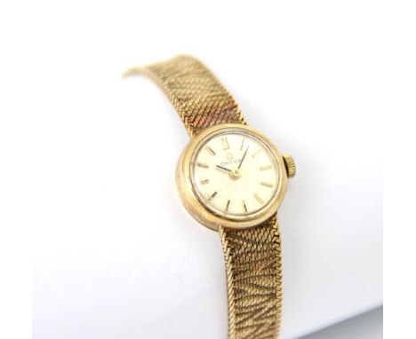 An Omega 9ct yellow gold ladies wristwatch, the circular cream dial with baton markers set to plain polished case, upon integ