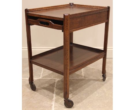 A vintage 1930’s oak cocktail trolley, the rectangular three quarter galleried upper tier with a removable butlers tray, over