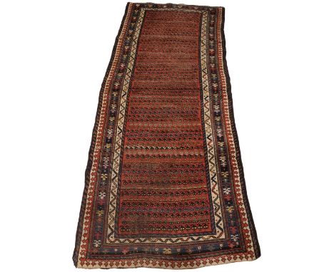 A hand knotted Persian wool runner, in red, blue, green and ivory colourways, the central red field with repeating rows of 'h