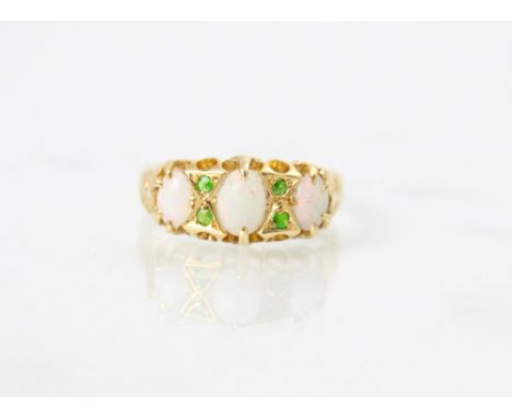 An 18ct yellow gold opal and demantoid garnet ring, the central oval cabochon opal with a further smaller opal set to each si