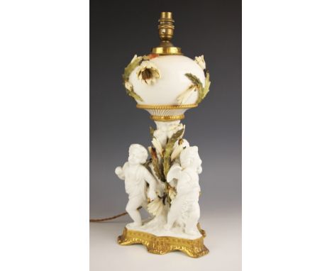 A blanc de chine figural lamp base in the manner of Minton, late 19th or early 20th century, modelled as three cherubs back t