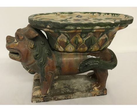 An oriental ceramic pedestal stand in the shape of a foo dog, with majolica style glaze.  Approx. 20cm tall x 29cm long.