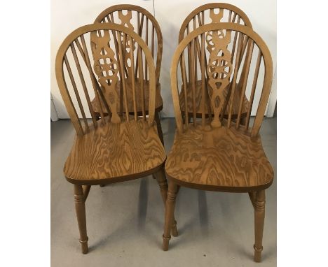 A set of 4 pine stick back kitchen chairs. With cartwheel motif to central back panel and turned legs. Approx. 90cm high.