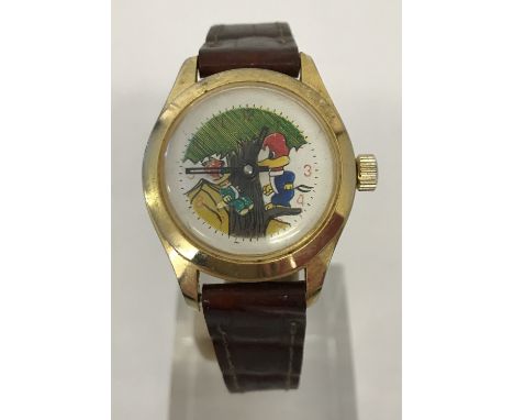 A vintage Woody Woodpecker wristwatch with rocking Woody detail to watch face. Gold tone case with a brown faux leather strap