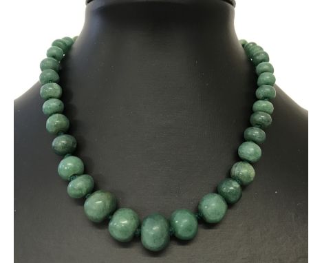 A graduating jade bead necklace with gold tone clasp and extension chain.  