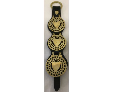 A vintage leather strap containing 3 love heart horse brasses.  Approx. 44cm long.