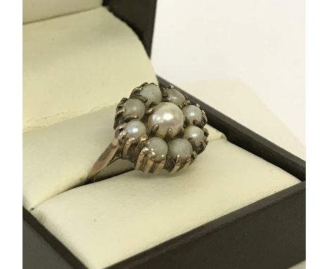 A vintage 9ct gold pearl dress ring. A central pearl surrounded by 8 smaller pearls. Surrounding pearls do have some wear. Si