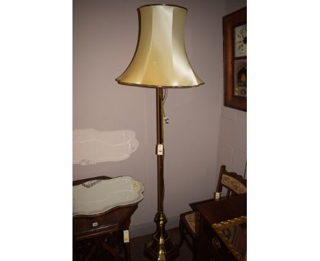 A modern brass standard lamp, raised on a wooden base, cream shade.