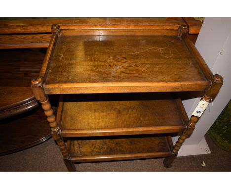 A mid 20th Century stained oak three-tier trolley, joined by bobbin turned columns, raised on metal castors.