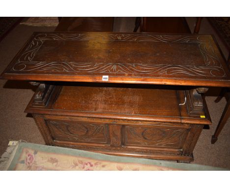 An early 20th Century oak monk's bench, the top and back with carved decoration, lion pattern arms, above carved panel below,