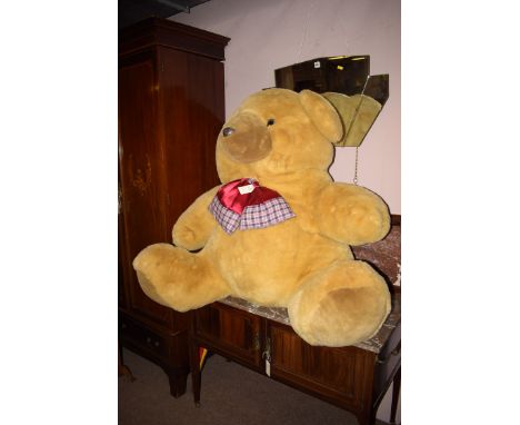 A giant teddy bear with a checked bow tie.
