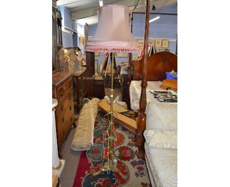 A Victorian brass standard lamp with three footed base and foliate decoration fitted with a pink shade